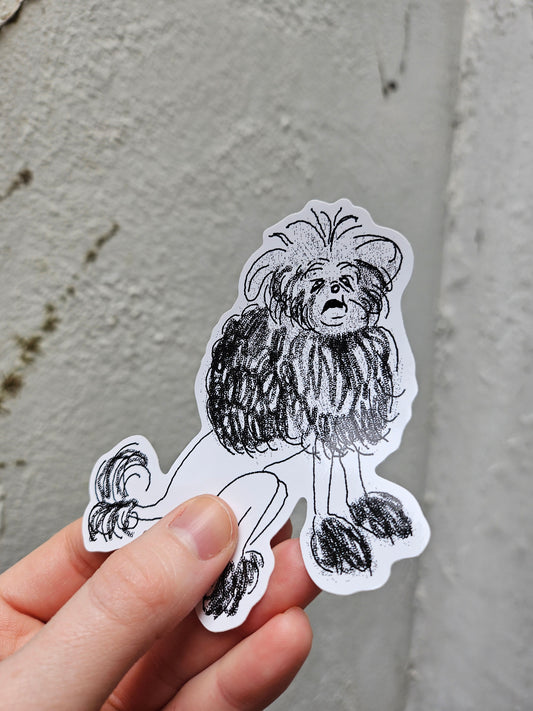 Hand holding a black and white illustrated sticker of an old, grumpy dog with long hair against a gray background